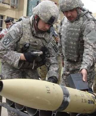 A U.S. soldier (L) inspects rockets which were found during ...