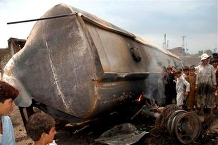 Children stand beside a burned Pakistani tanker, which was carrying ...