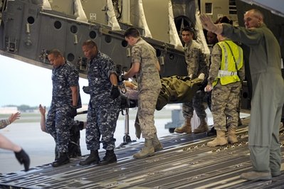 A wounded U.S. soldier is carried off of a C-17 ...